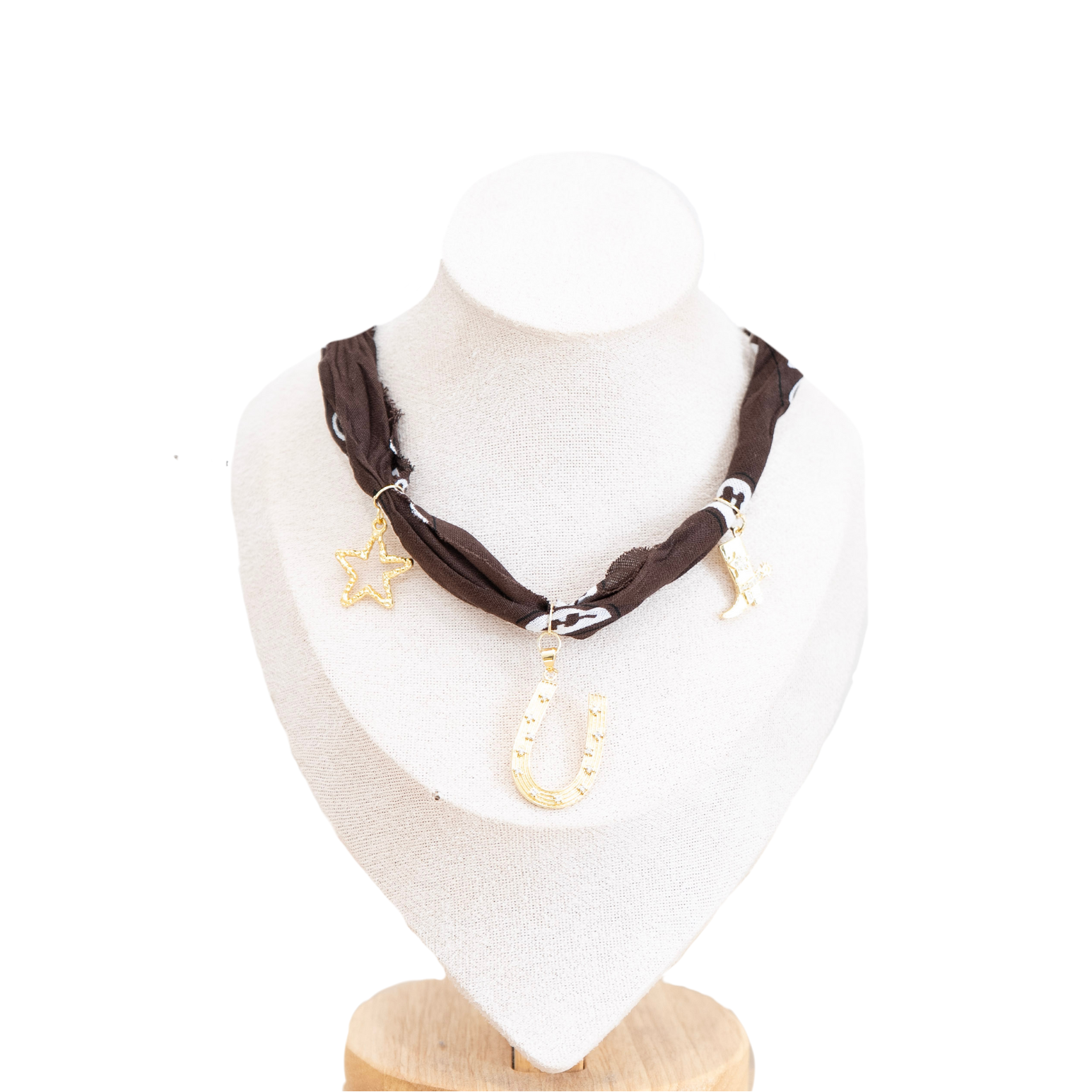 A dark brown fabric choker necklace with dangling charms, including a gold star, a gold horseshoe, and a silver crescent moon, displayed on a white mannequin bust.