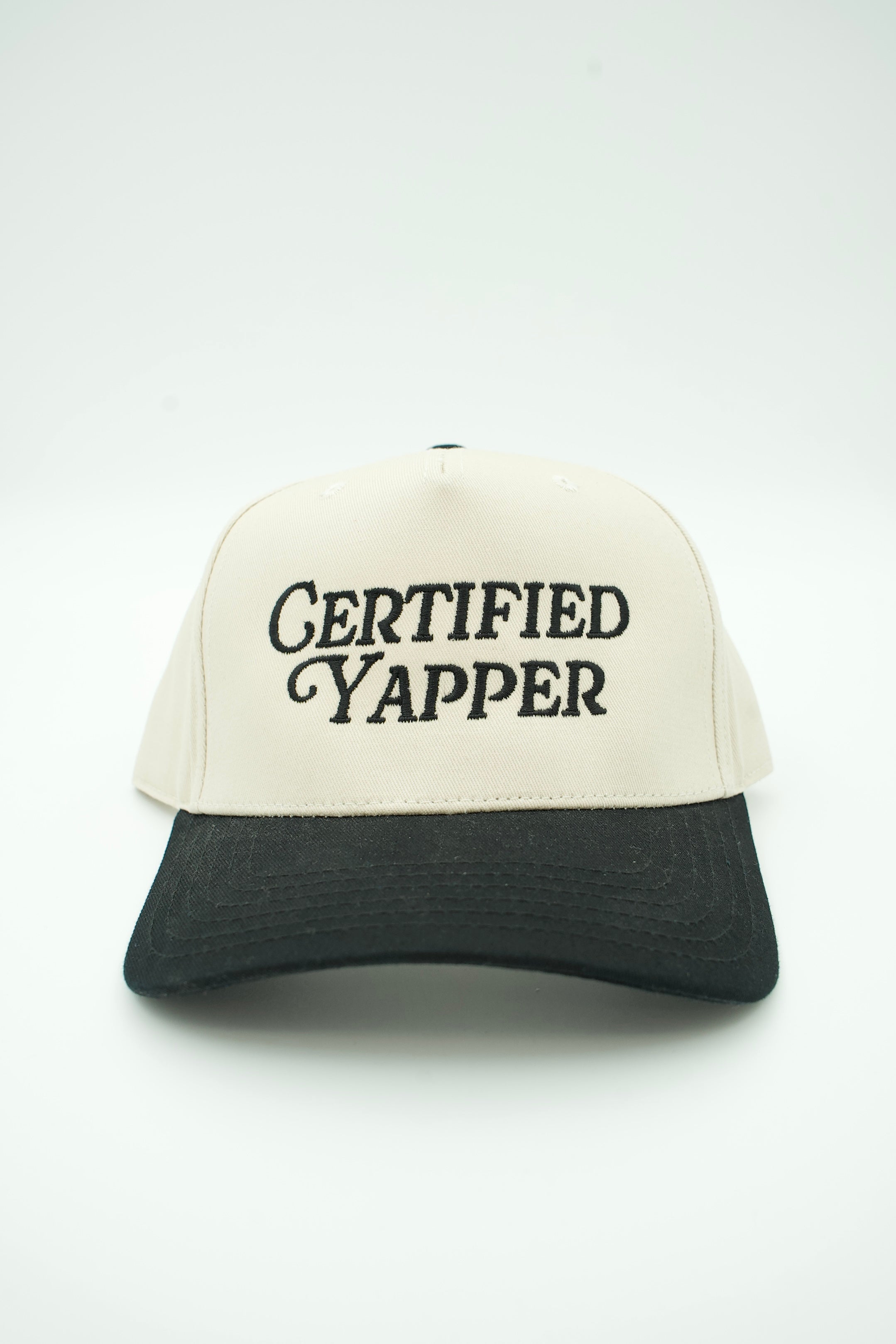 A two-tone baseball cap with an off-white front panel and brim, and a black mesh back and brim underside. The front panel features the embroidered text 'CERTIFIED YAPPER' in black.