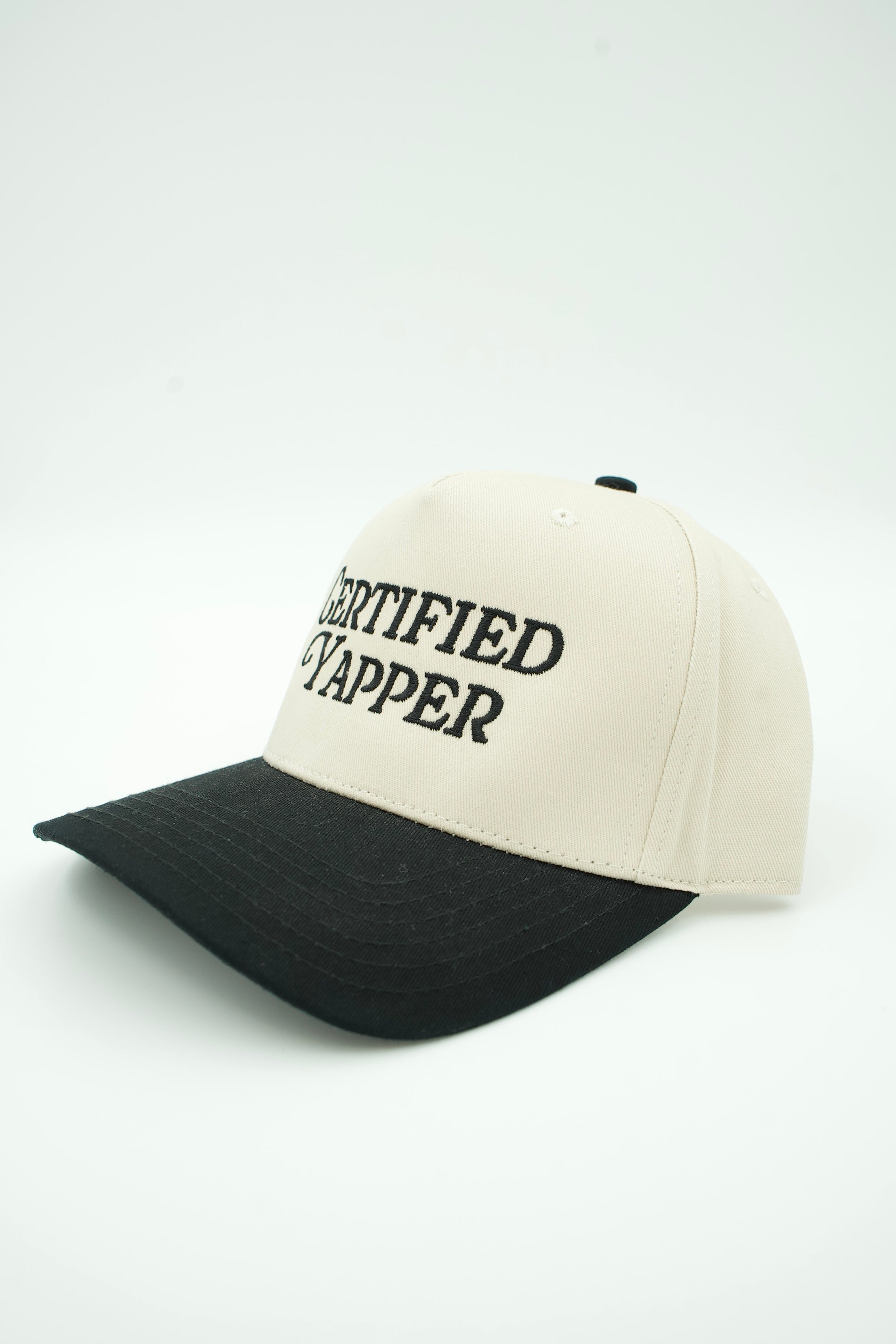 A two-tone baseball cap with an off-white crown and a black curved brim, featuring the text 'CERTIFIED YAPPER' embroidered in black on the front.