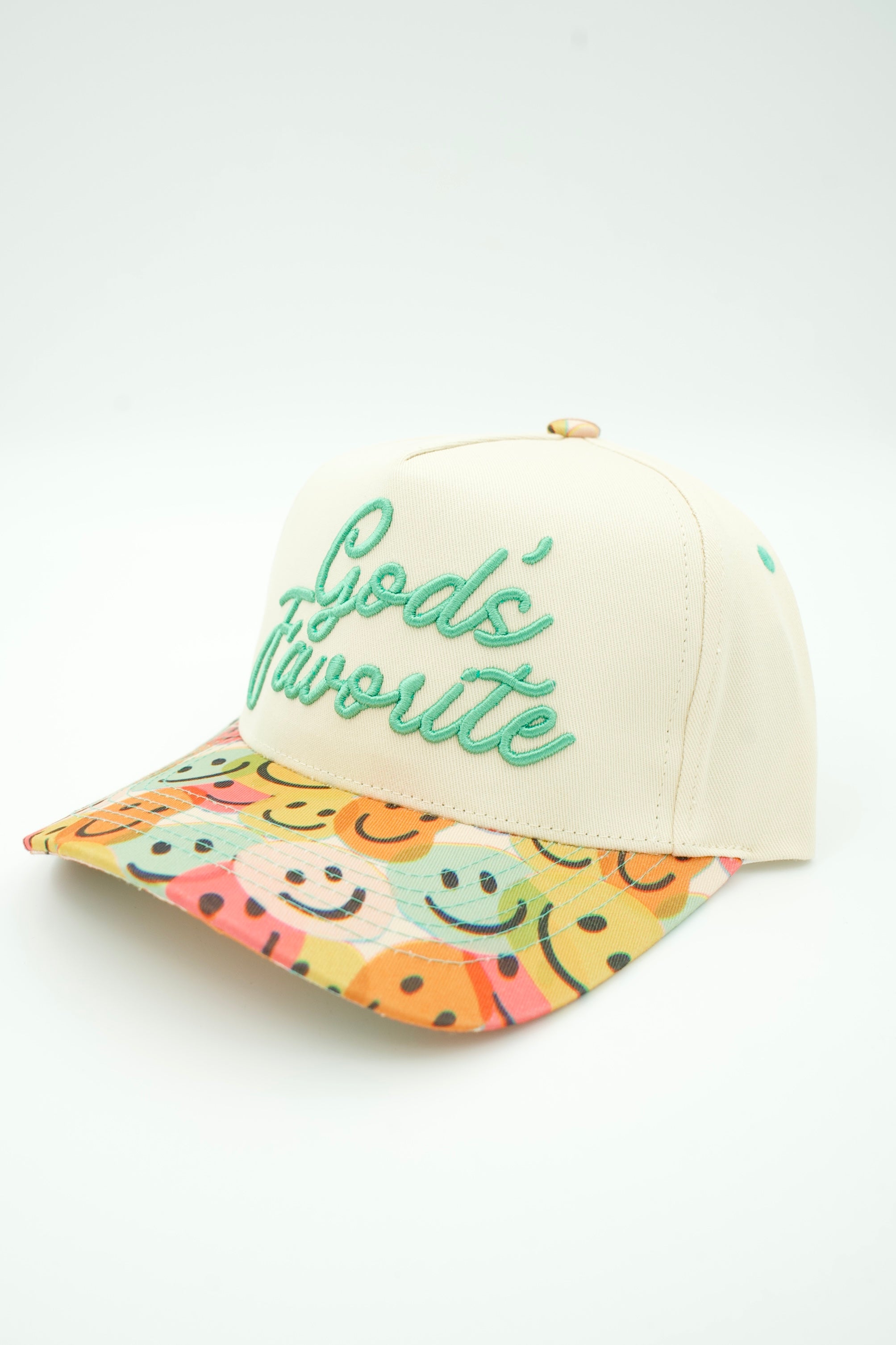 An off-white baseball cap with 'God's Favorite' embroidered in green on the front, featuring a colorful patterned brim with smiley faces.