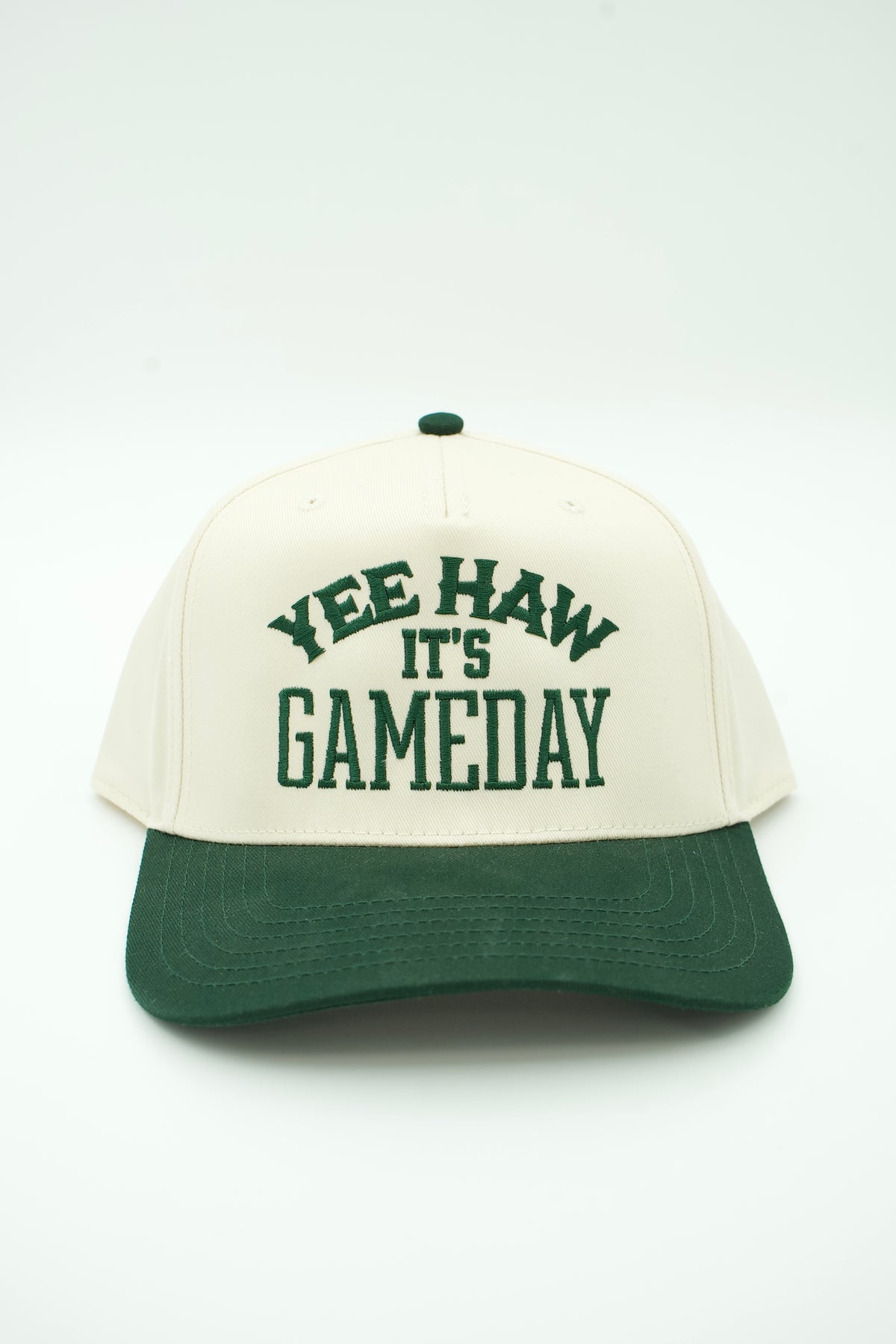Front image of cream canvas trucker hat with green embroidered "YEE HAW IT'S GAME DAY" and a green bill