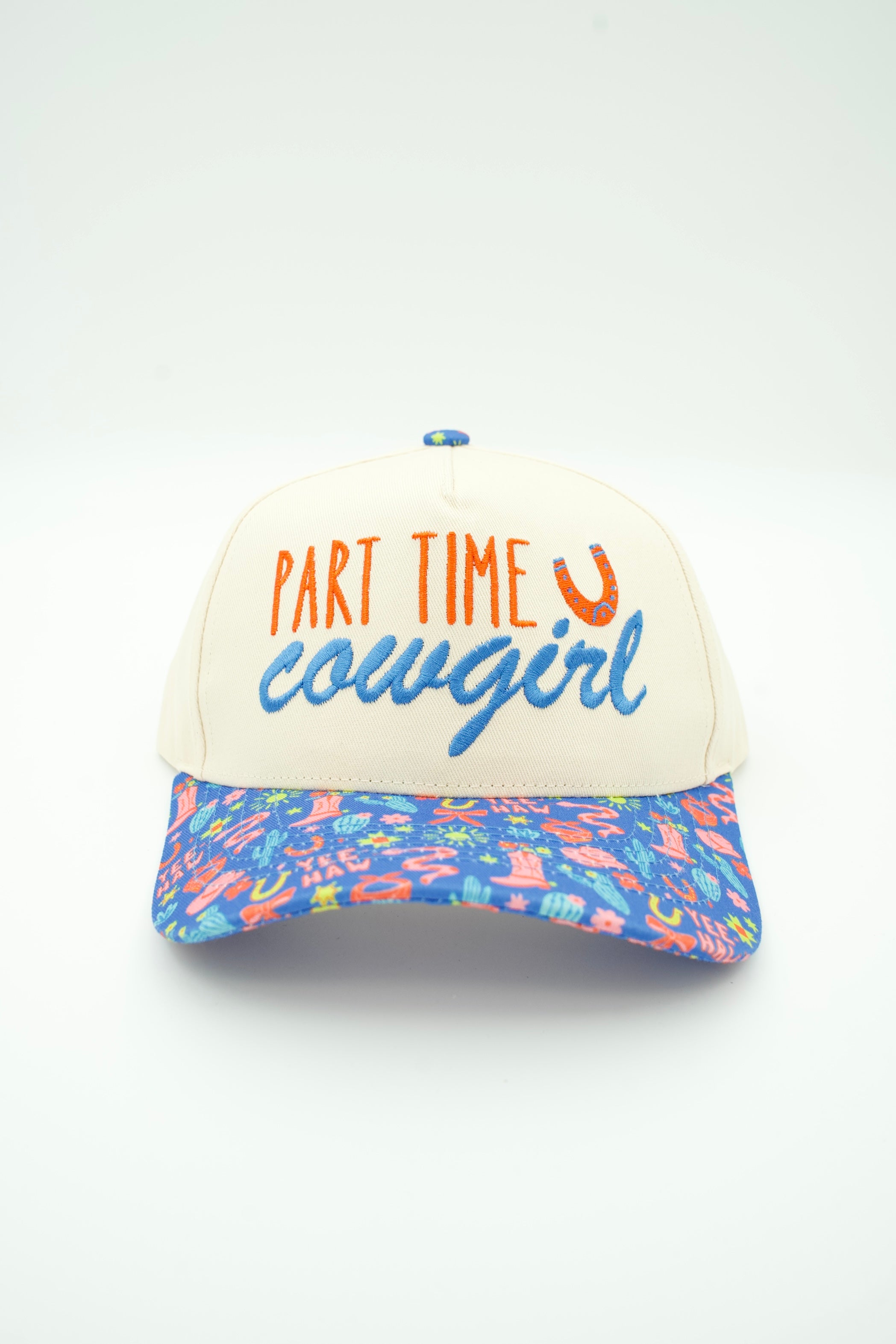 A trucker hat with an off-white crown featuring the embroidered text 'PART TIME cowgirl' in orange and blue, and a vibrant, multicolored floral patterned visor.