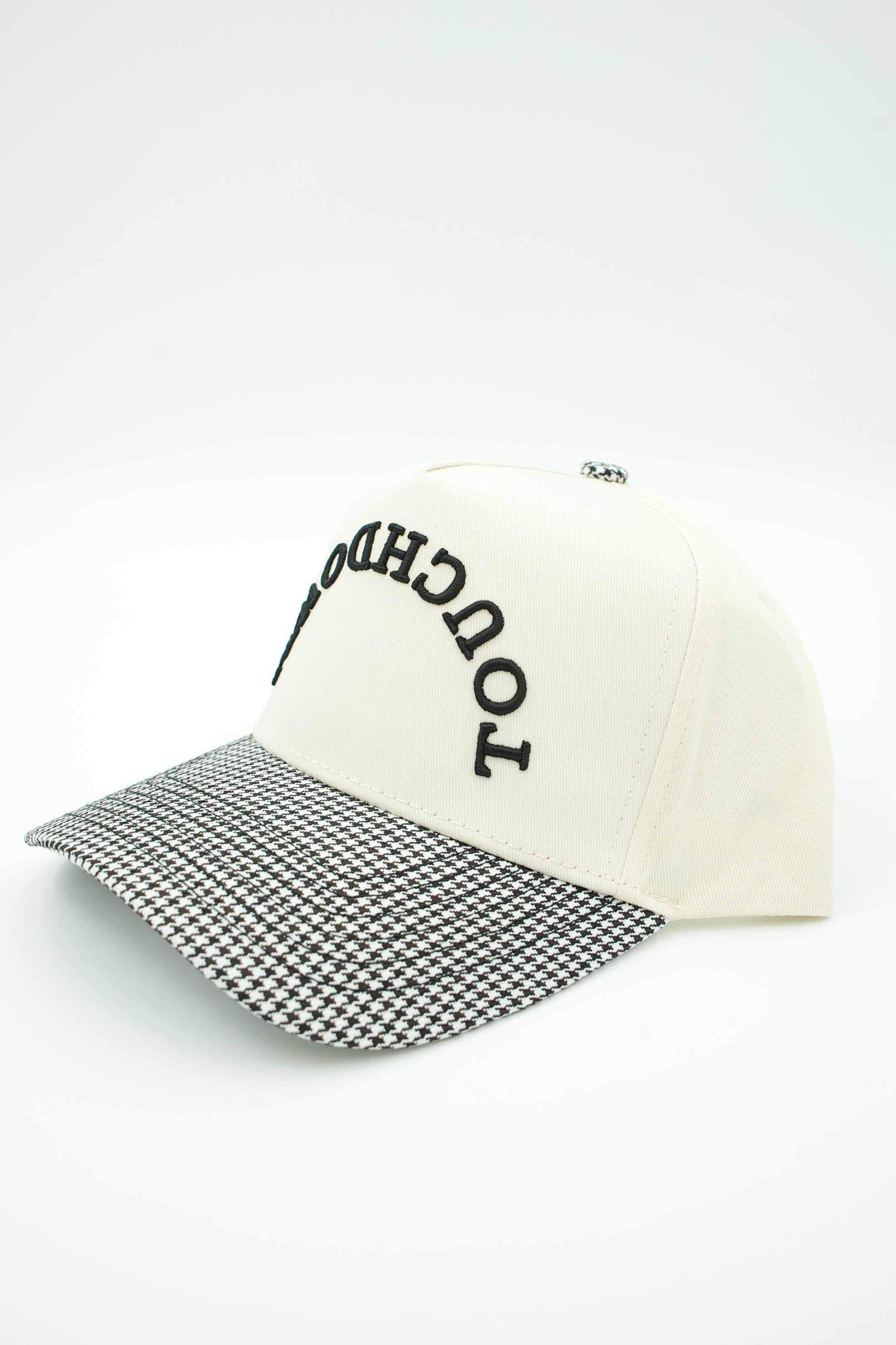 An off-white baseball cap with a black-and-white houndstooth patterned visor and black embroidered text reading 'TOUCHDOWN' on the front, shown on a clean white background.