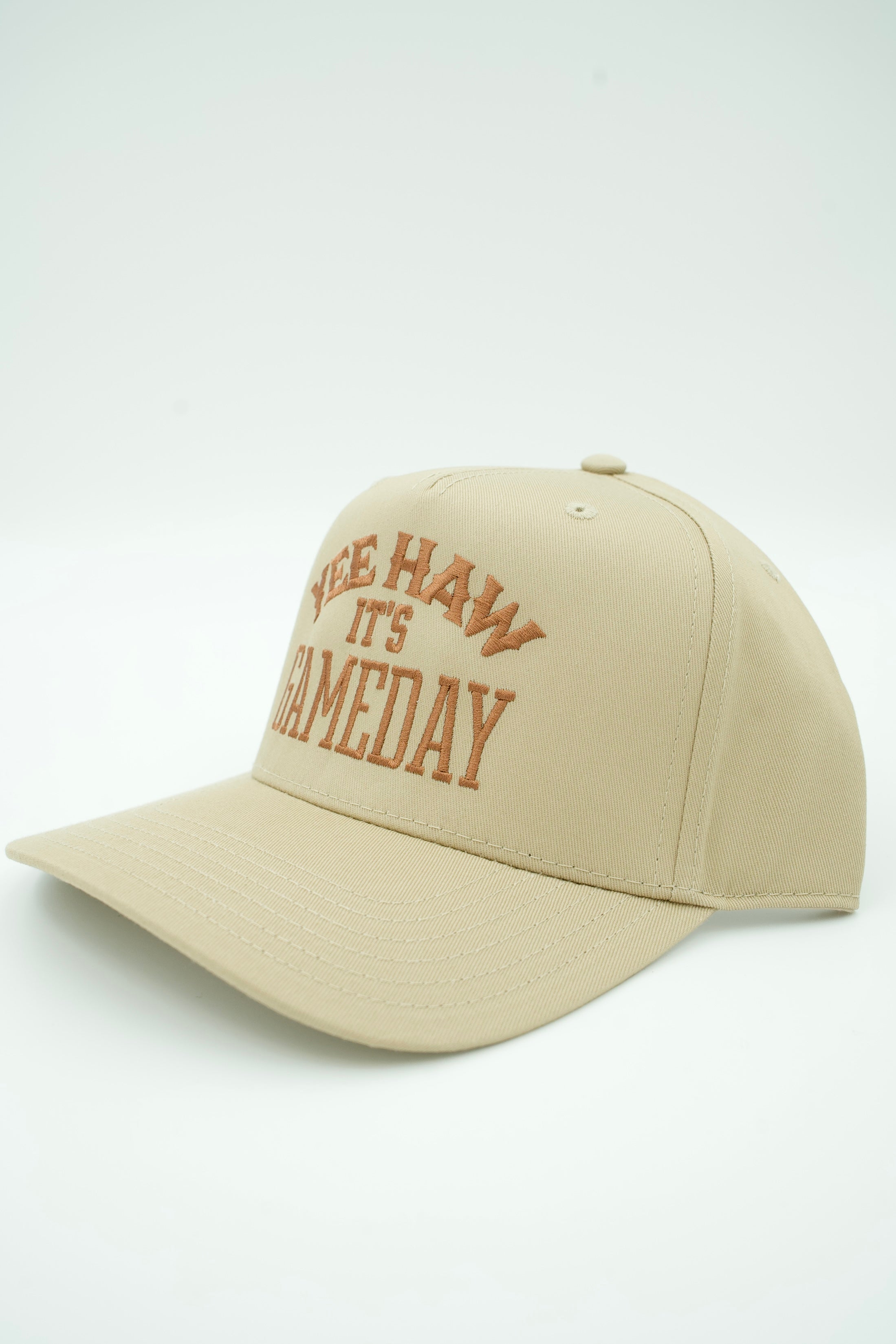 A beige baseball cap with brown embroidered text reading 'SKELETON HAWK IT'S GAMEDAY' on the front, photographed on a clean white background.