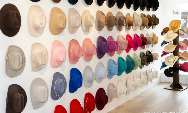 Image of a wall with a colorful assortment of cowboy hats hanging on it