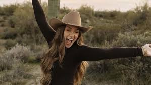 Happy woman stretching her arms in a cowboy hat in the desert