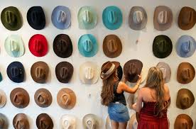 Two people looking at a colorful wall of cowboy hats