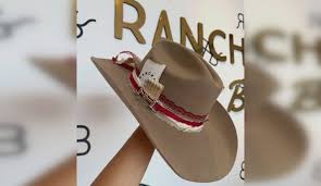 Image of a tan cowboy hat decorated with ribbon, cards and matches