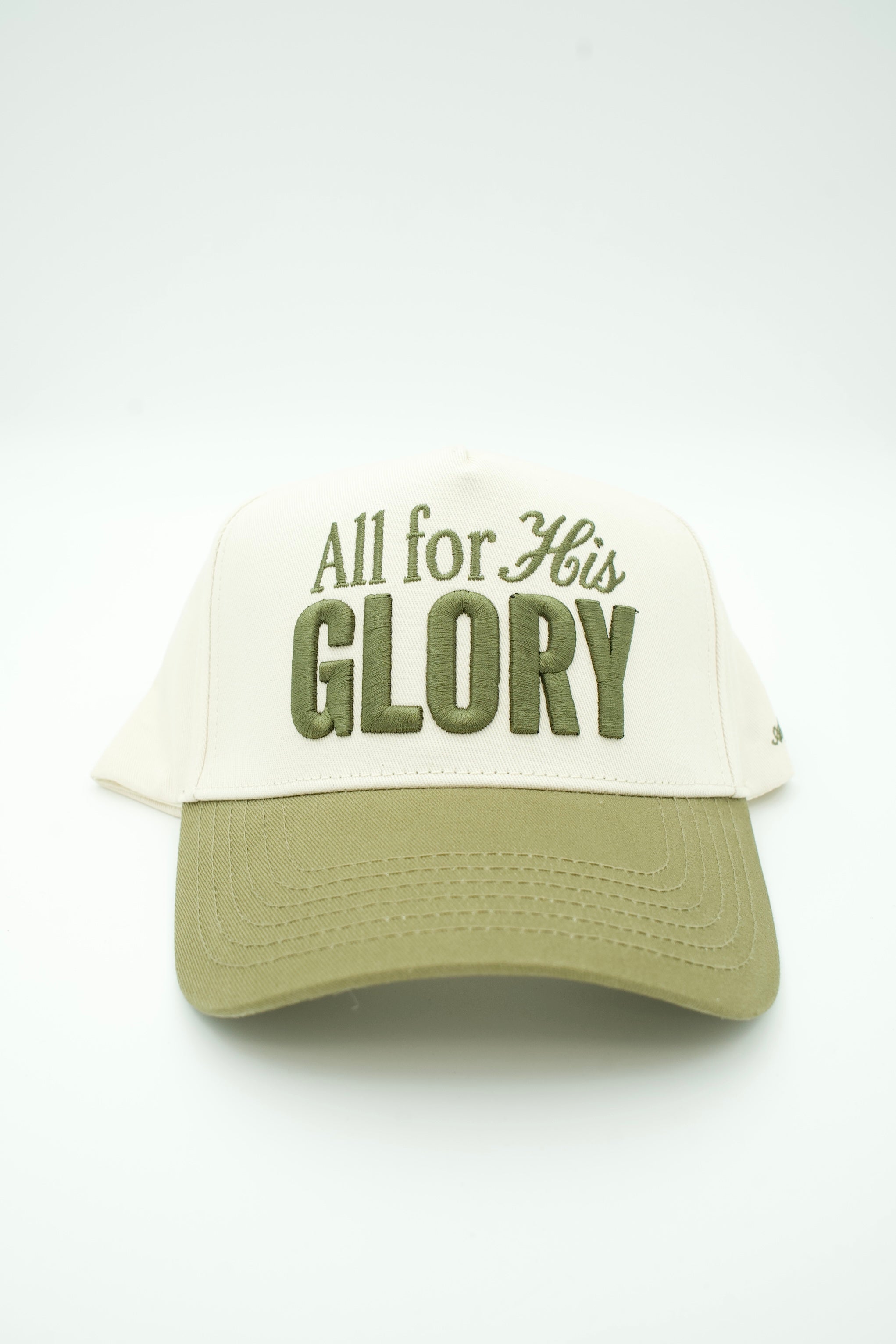 A trucker-style hat with an off-white front panel and brim in olive green, featuring the embroidered text 'All for His GLORY' on the front.