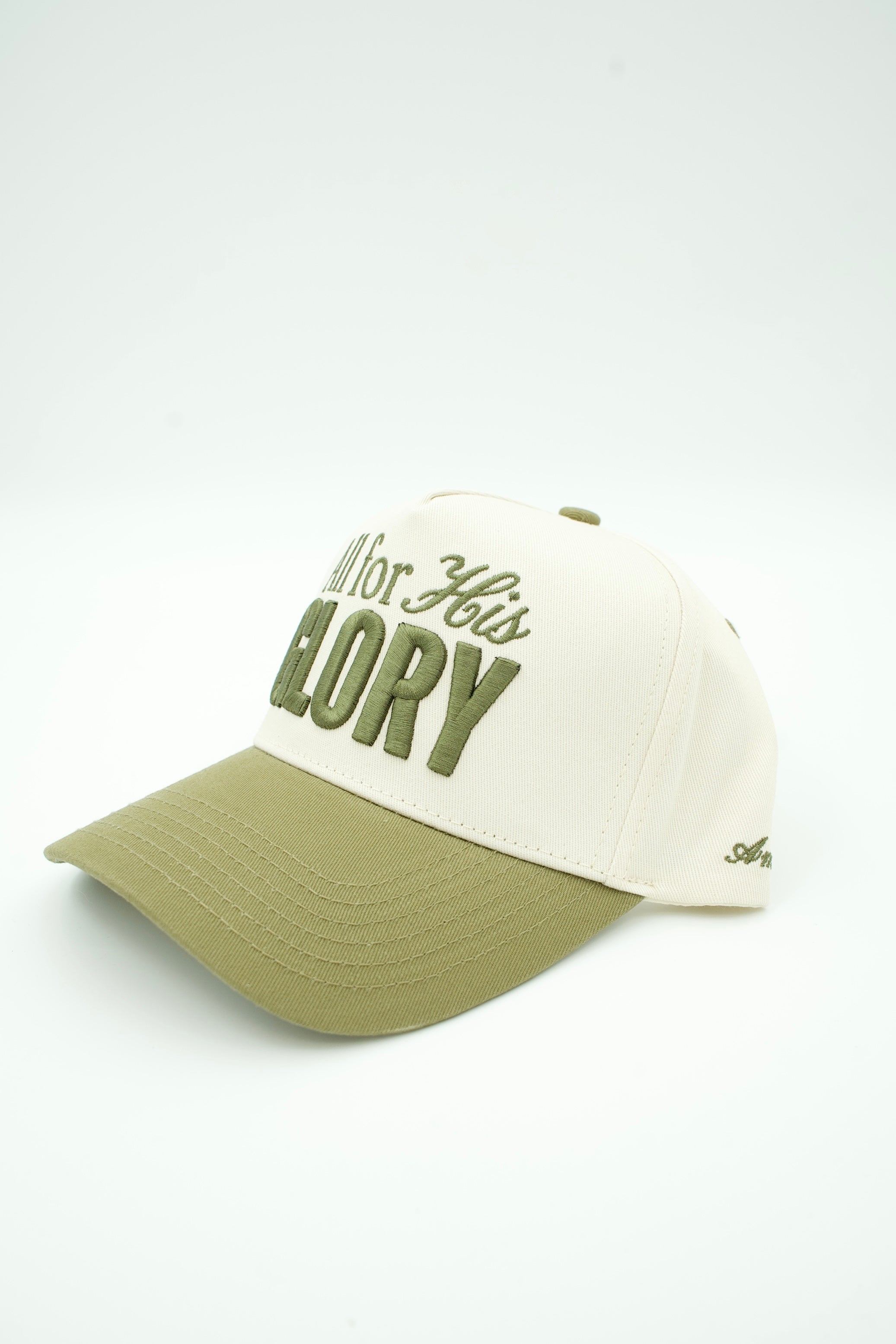 A baseball cap with an off-white crown and an olive green brim, featuring embroidered text on the front that reads 'All for His Glory' in olive green.