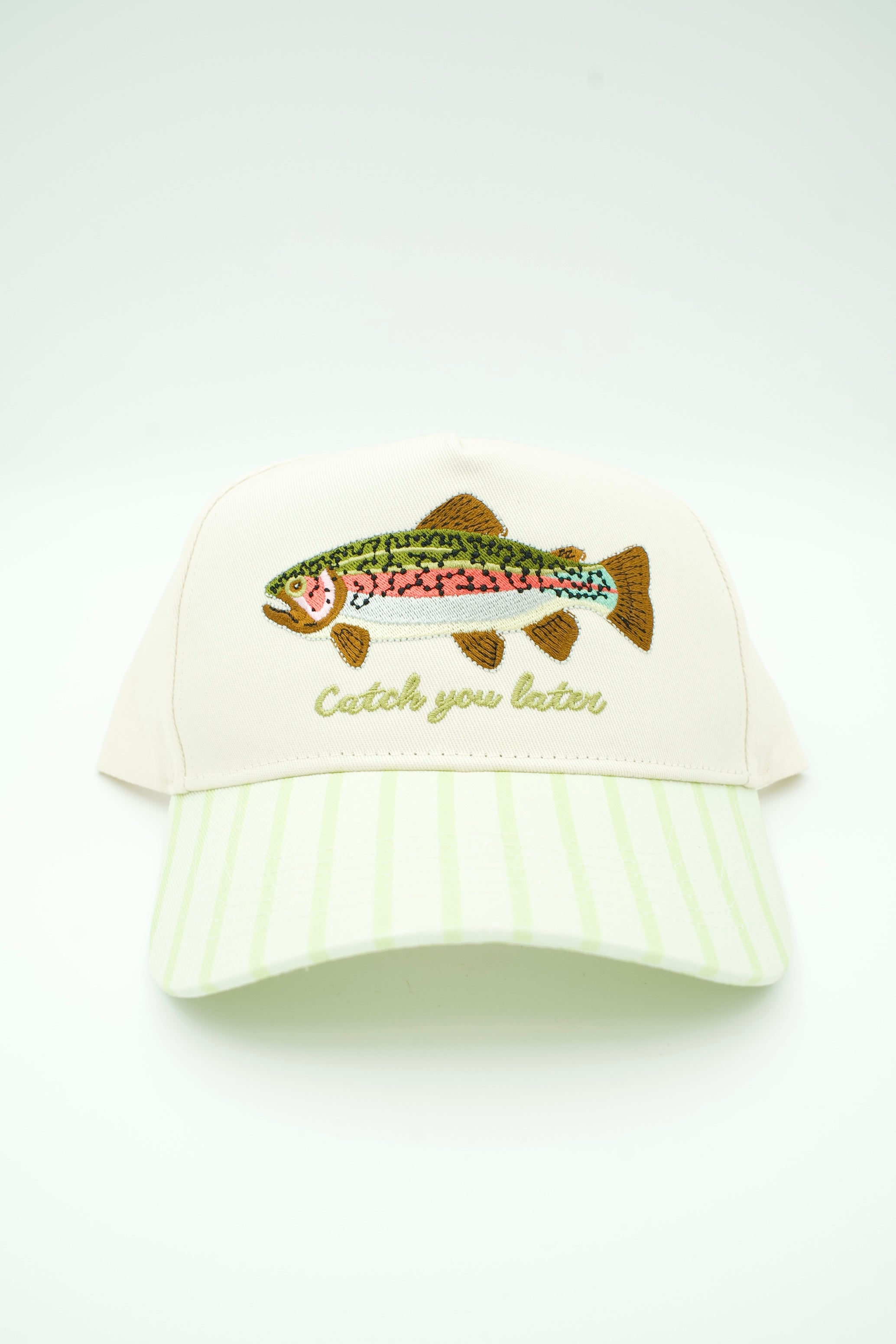 An off-white baseball cap with a light green and white striped visor, featuring an embroidered rainbow trout and the phrase 'Catch you later' in gold thread on the front.