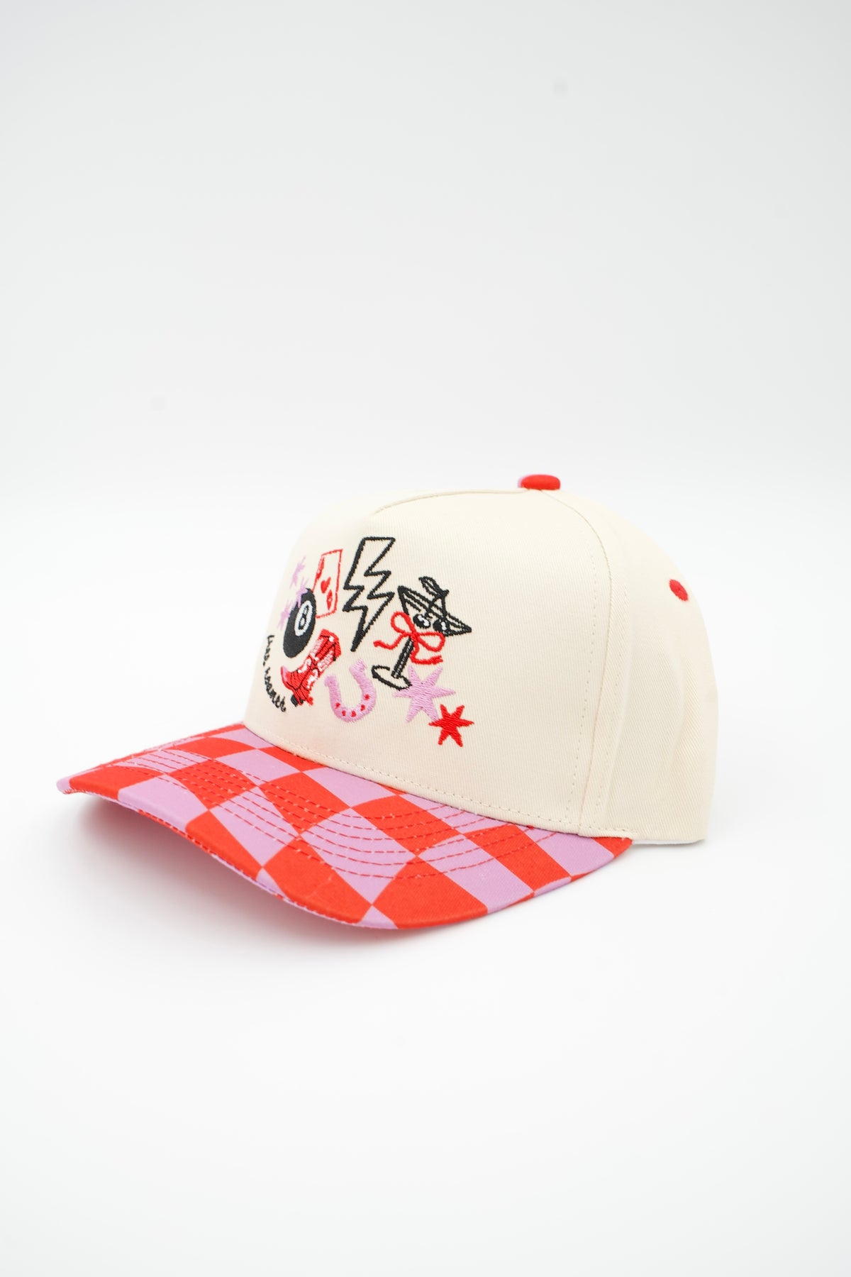 Side image of cream canvas trucker hat with "Free Roamer" embroidered and eight ball cowboy boot, horse shoe and ace card embroidered designs with a pink and red checkered bill. 