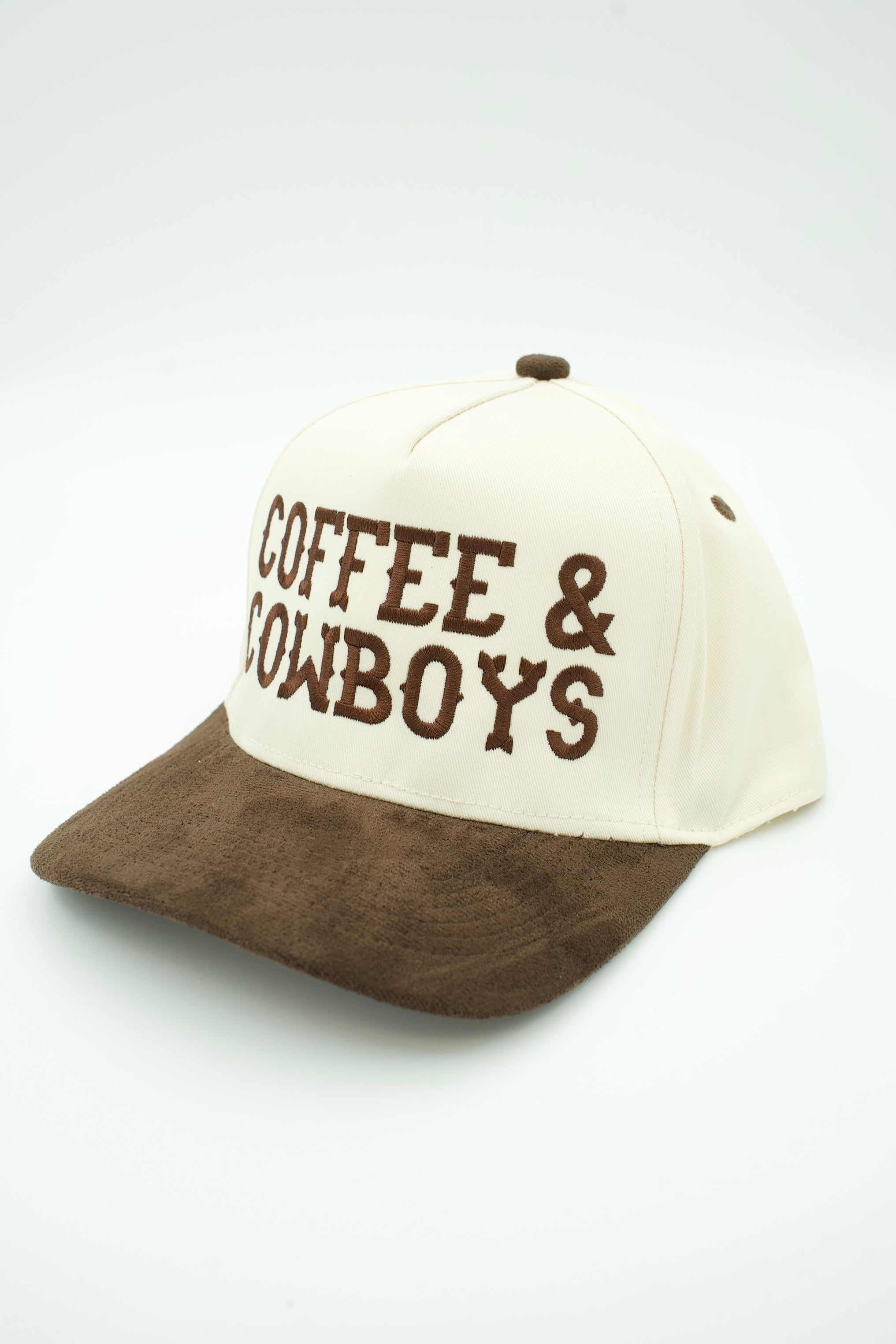 A baseball cap with an off-white crown and a brown suede-look brim, featuring the words 'COFFEE & COWBOYS' embroidered in brown on the front.