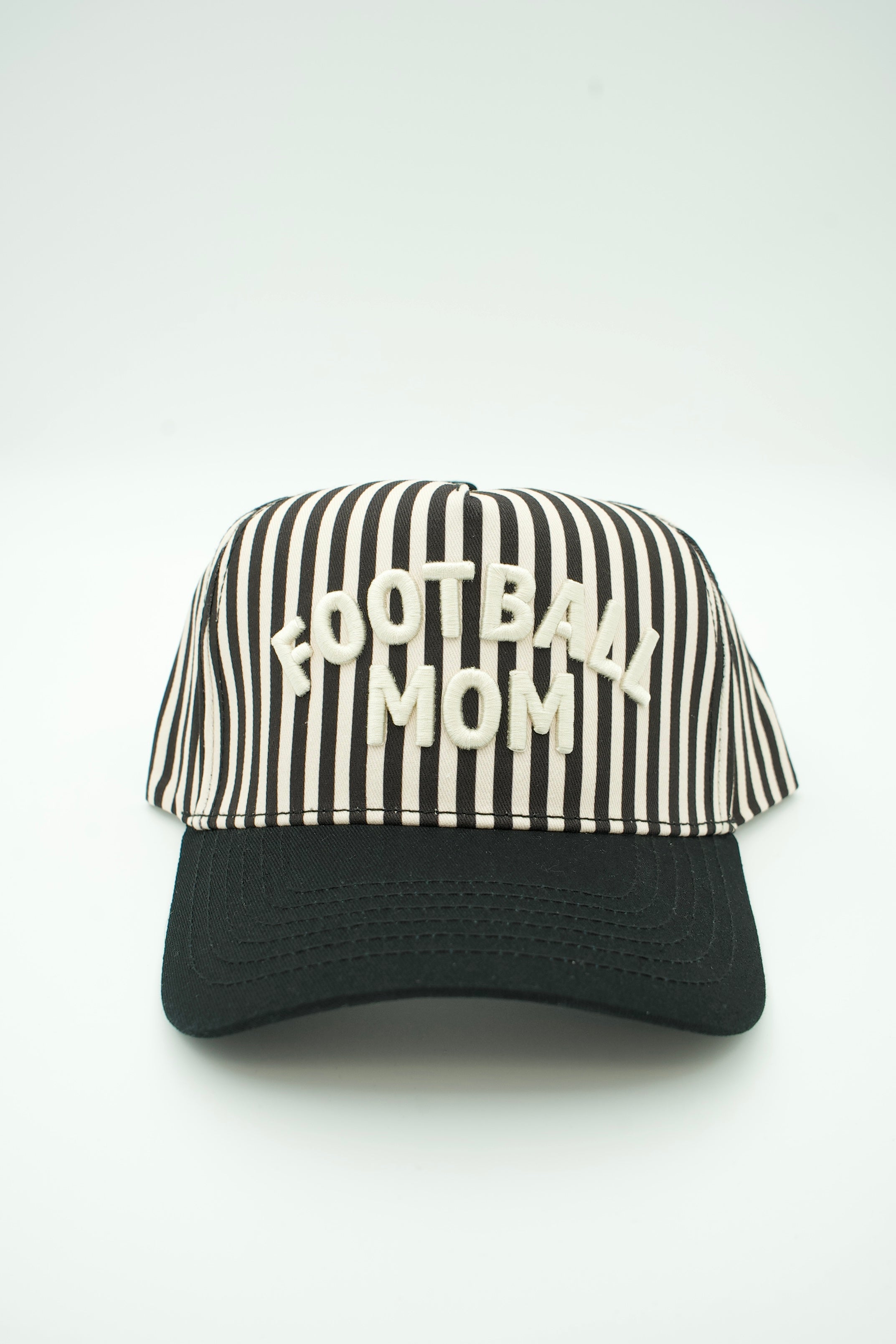 A baseball-style cap with a black and off-white vertically striped front panel and brim, featuring the words 'FOOTBALL MOM' embroidered in off-white across the front. The cap is photographed against a plain white studio background.