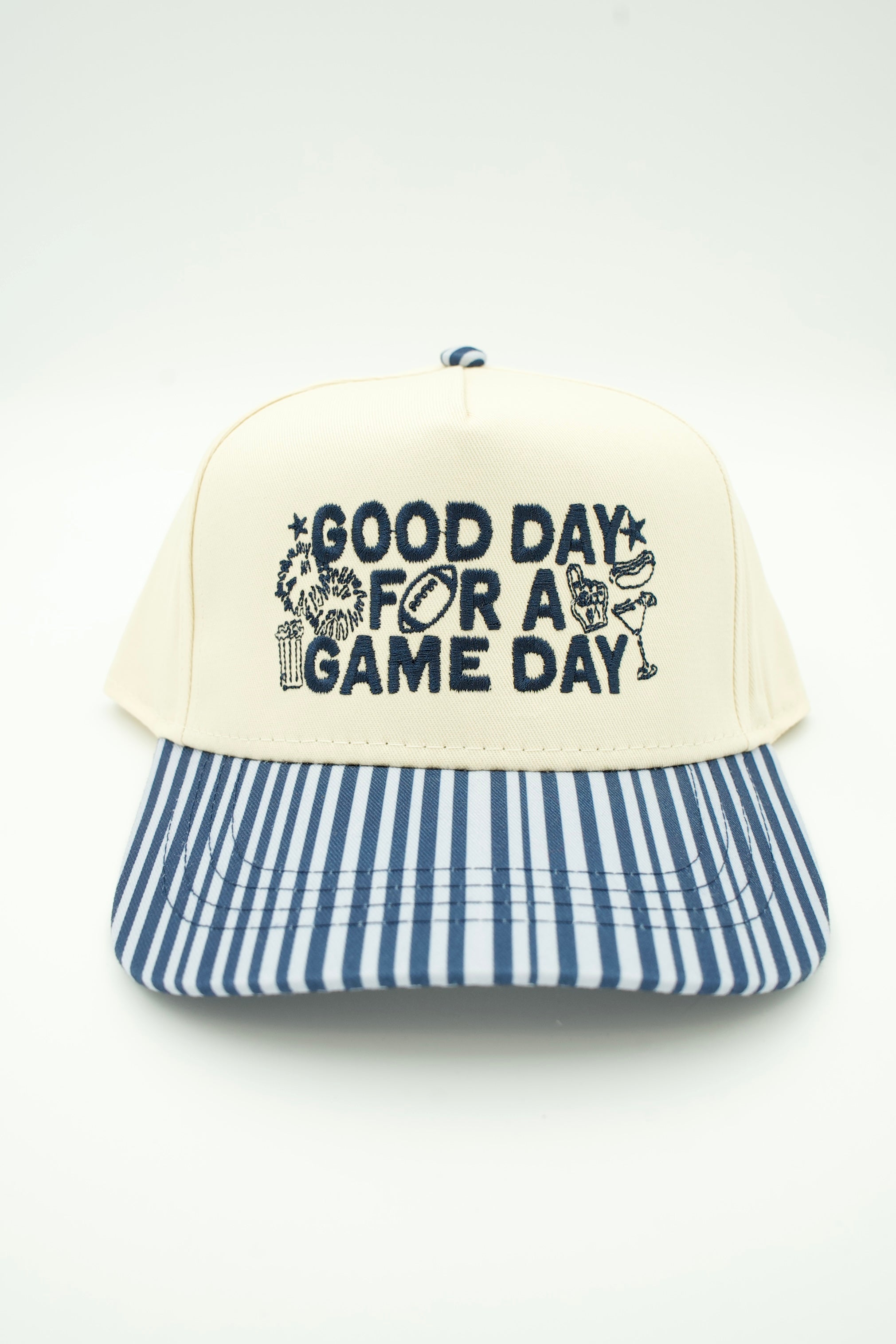 A baseball cap with an off-white front panel featuring the text 'GOOD DAY FOR A GAME DAY' in navy blue, and a blue and white vertically striped brim.