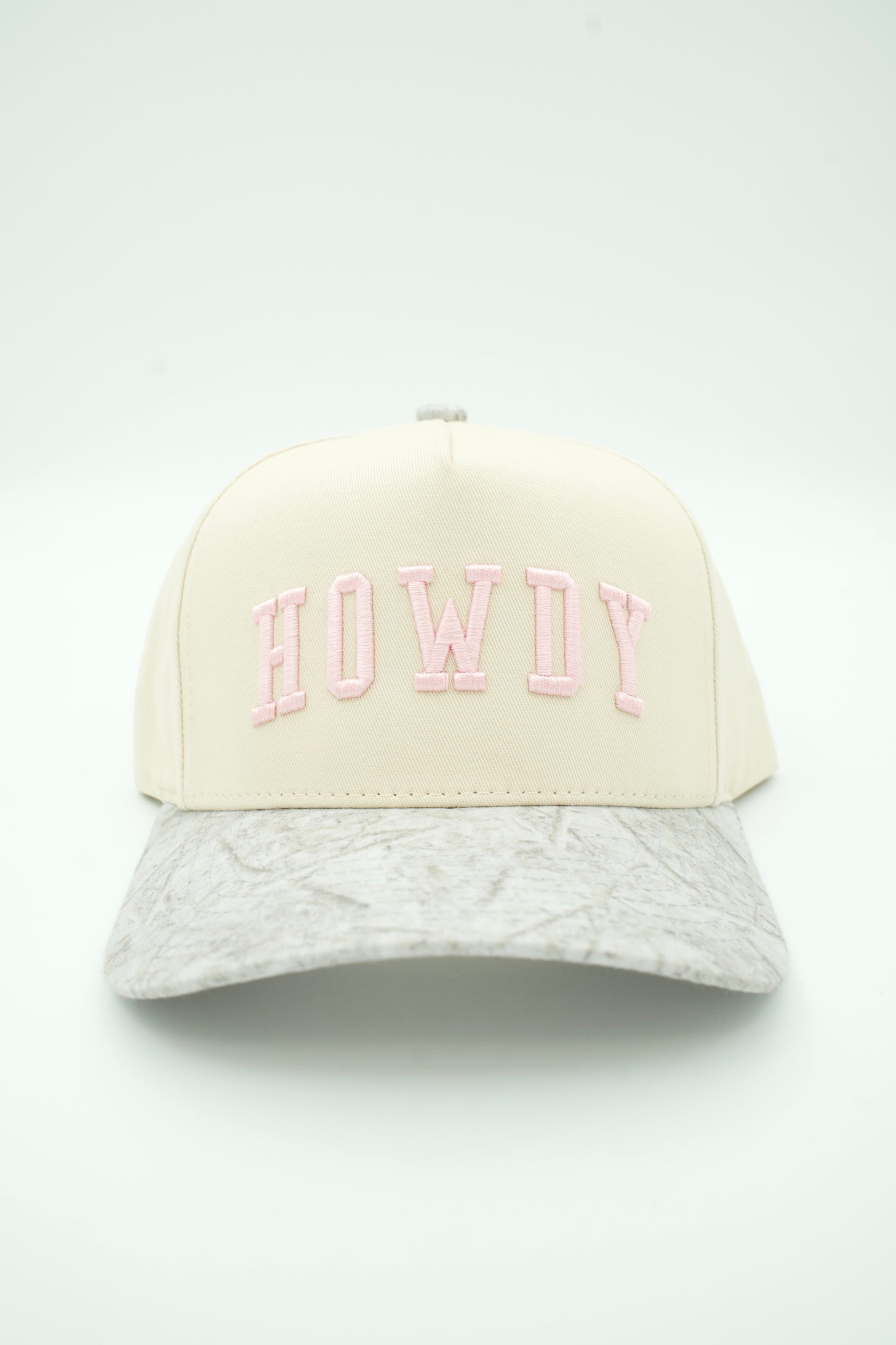 A structured baseball cap with a cream-colored crown and a light gray marbled brim, featuring the word 'HOWDY' embroidered in pink arched letters on the front.