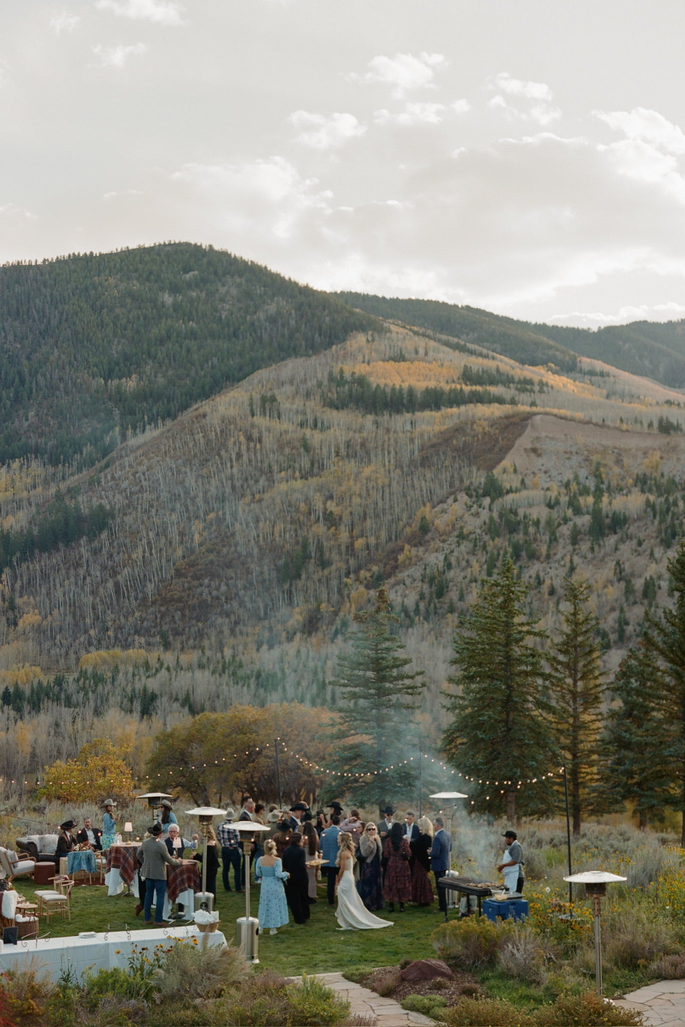 Outdoor wedding reception with guests in a mountainous landscape