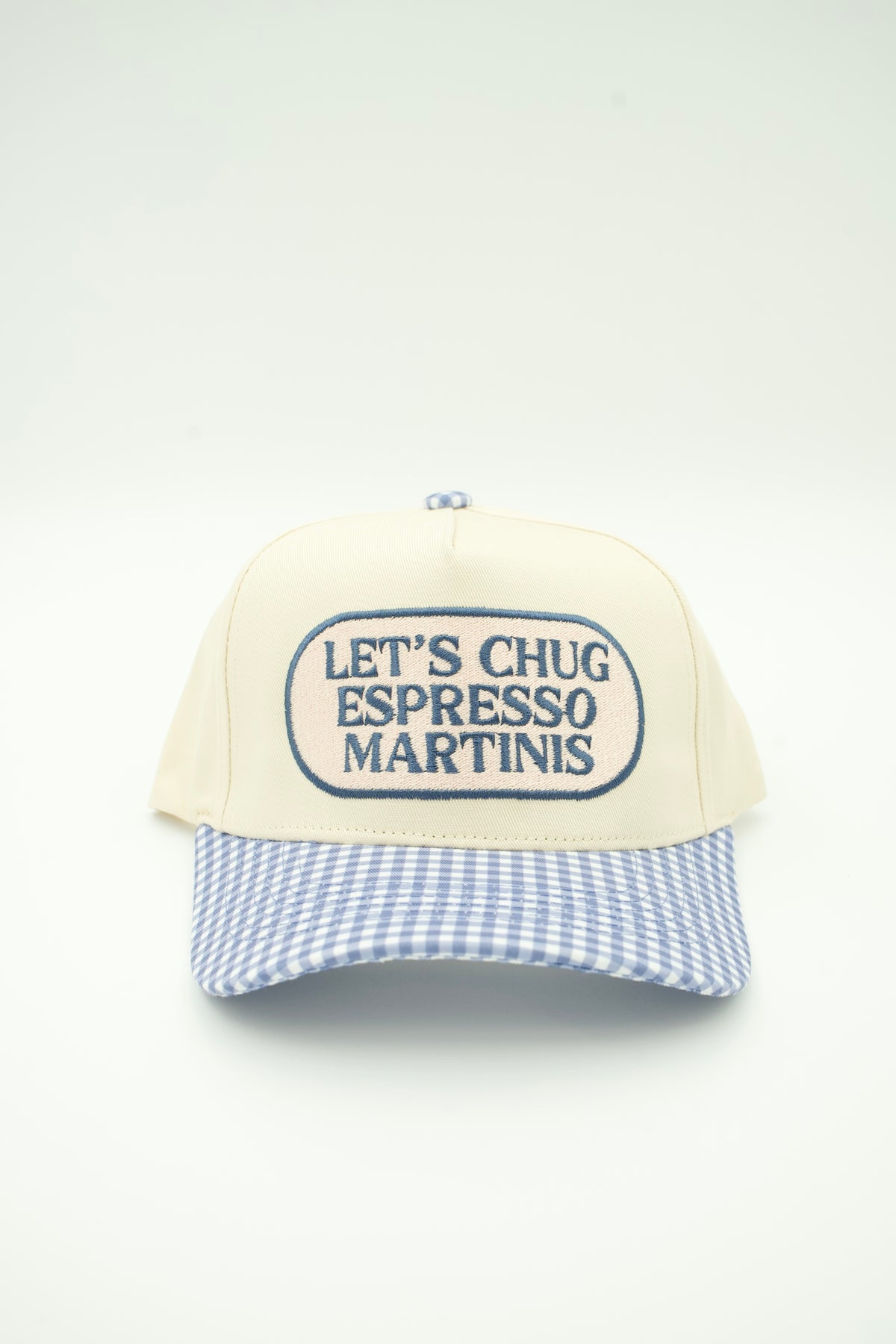 A trucker-style baseball cap with an off-white front panel featuring the embroidered text 'LET'S CHUG ESPRESSO MARTINIS' in navy blue, and a light blue and white gingham checkered brim, shown against a plain white background.