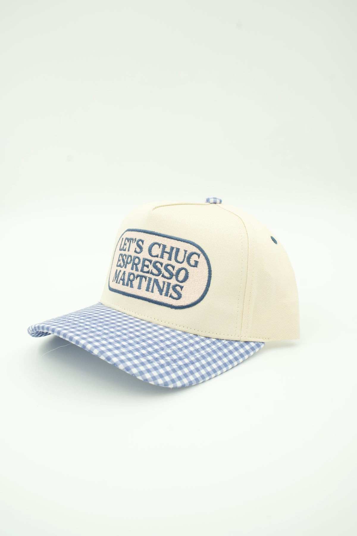 A cream-colored baseball cap with a blue and white gingham checkered brim. The front panel features a blue embroidered oval logo that reads 'LET'S CHUG ESPRESSO MARTINIS'.