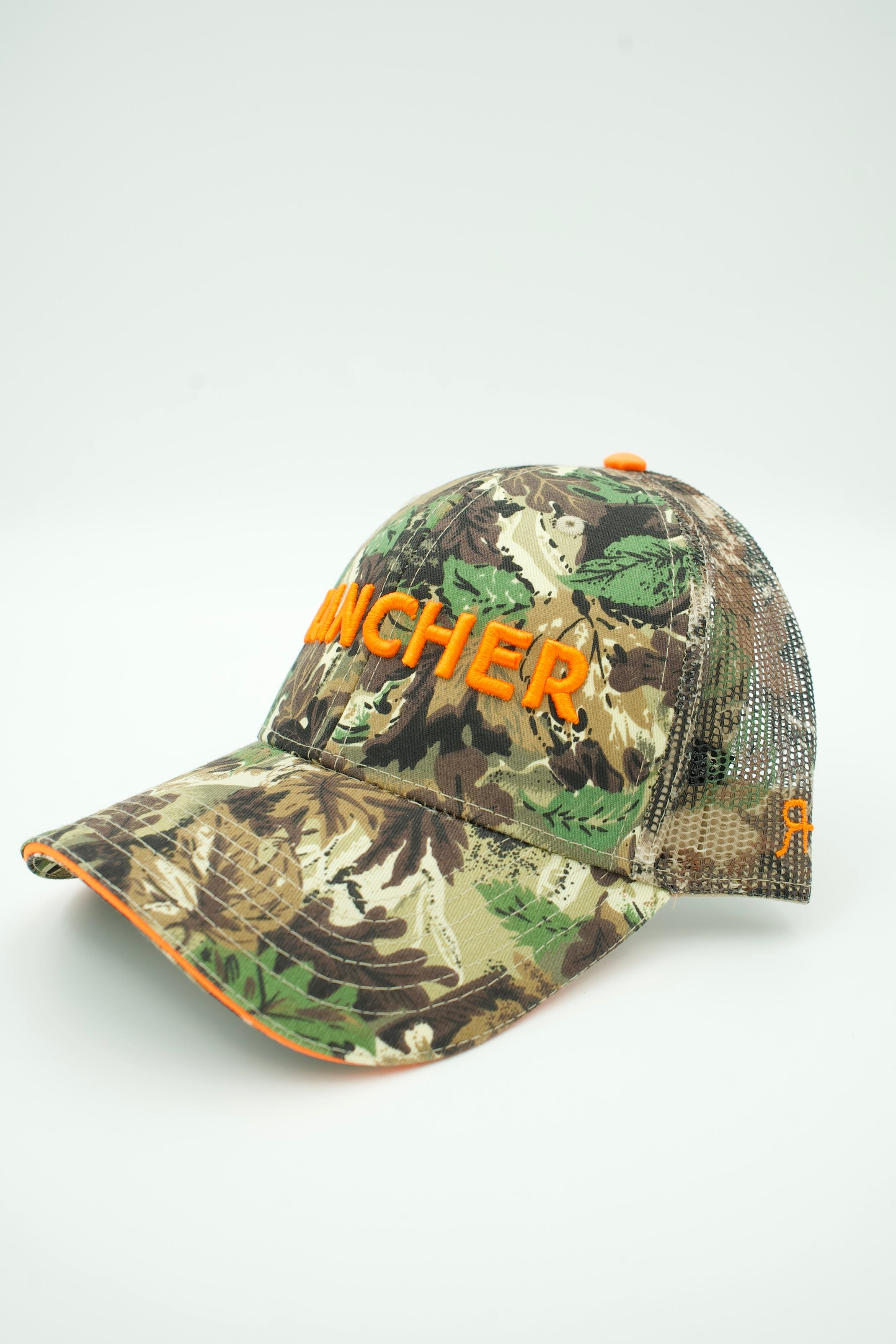 A camouflage trucker hat with orange embroidered 'RANCHER' text on the front, shown on a light gray background.