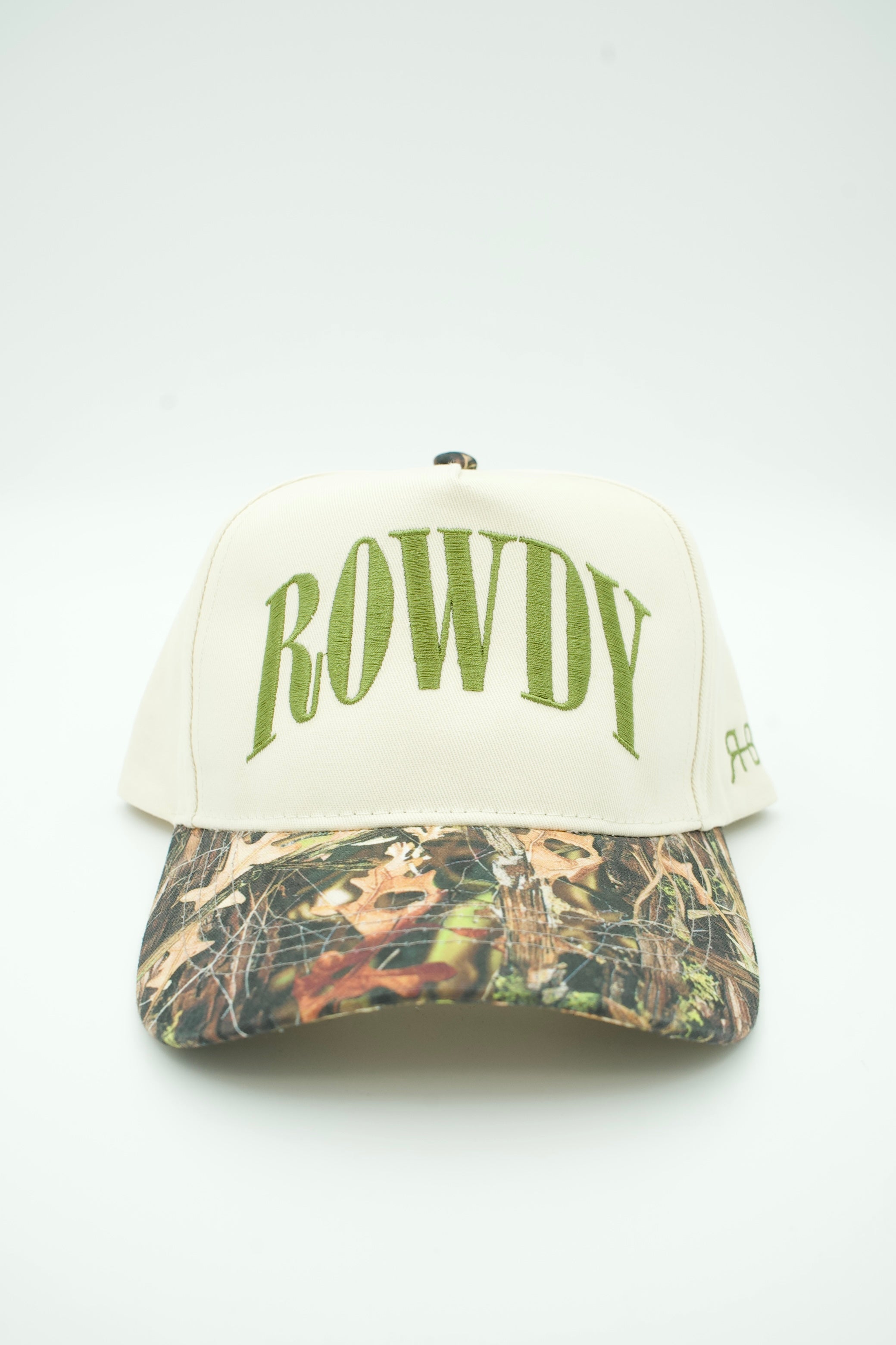 A baseball cap with an off-white crown featuring the word 'ROWDY' embroidered in green arched letters, and a camouflage patterned visor.