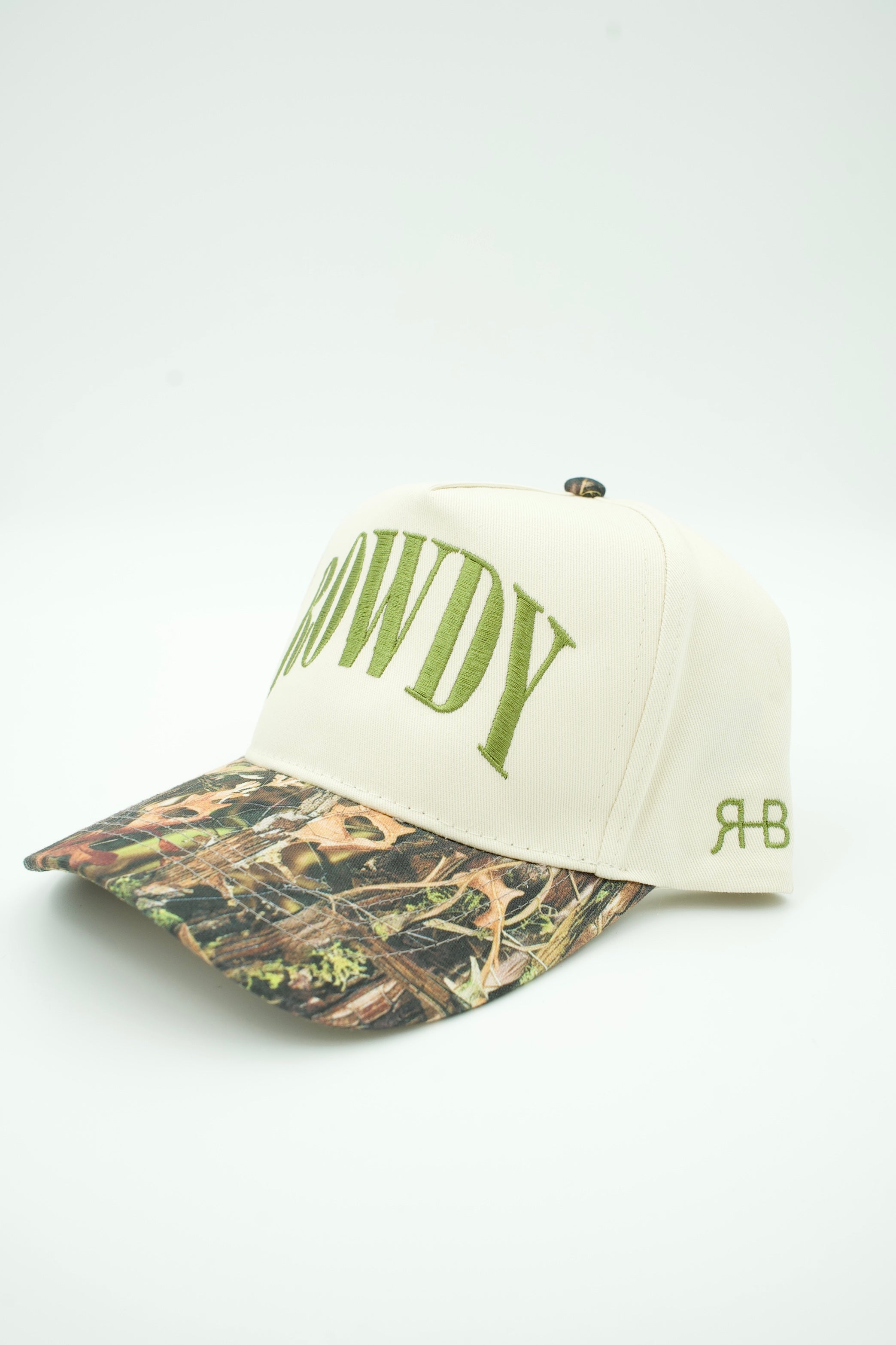 An off-white baseball cap with green embroidered 'COWDY' text on the front and a camouflage-patterned brim, shown on a plain white background.