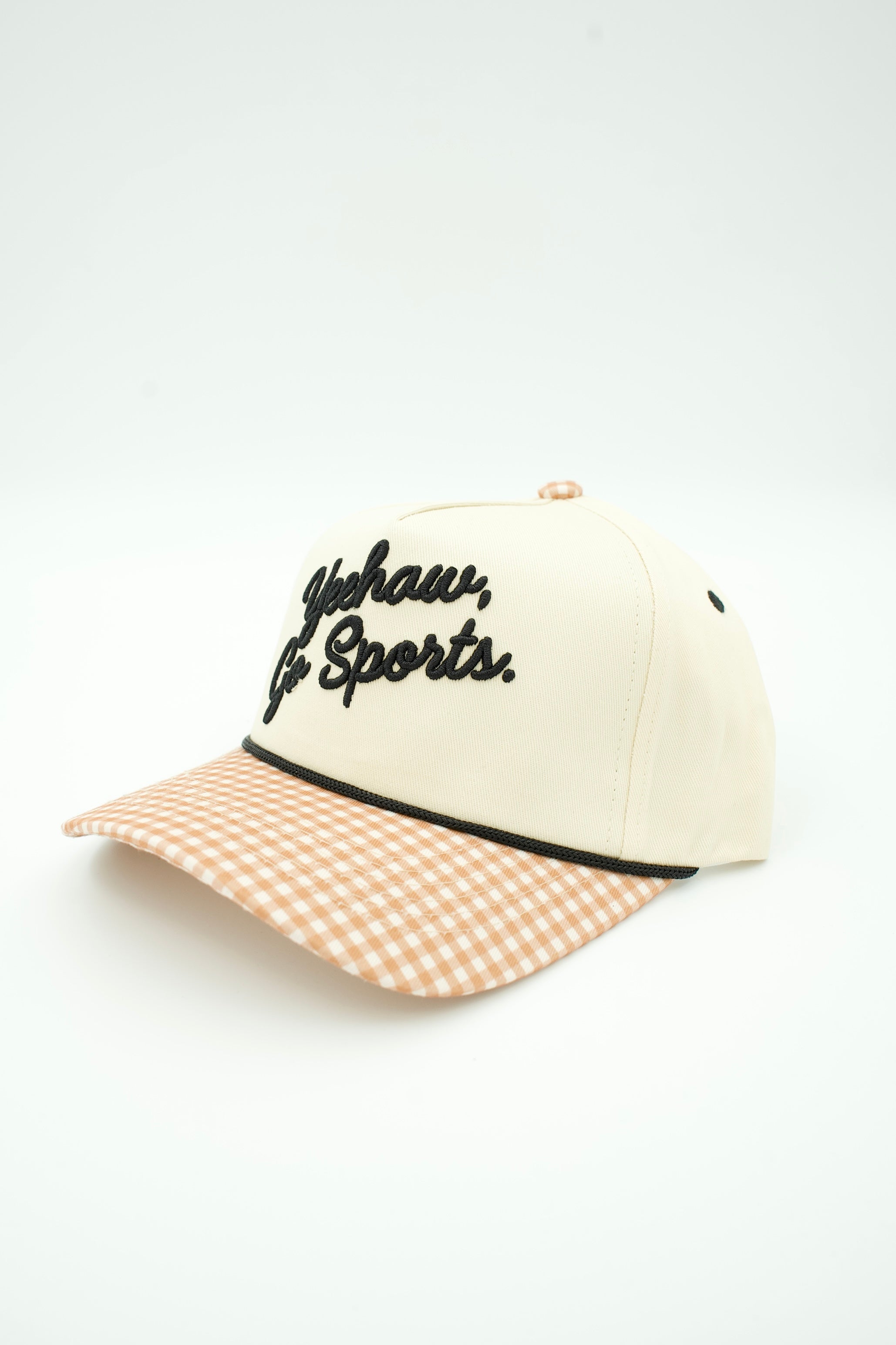 An off-white baseball cap with black embroidered text reading 'Yeehaw Go Sports.' on the front, featuring a peach and white gingham checkered visor and black piping along the edge.